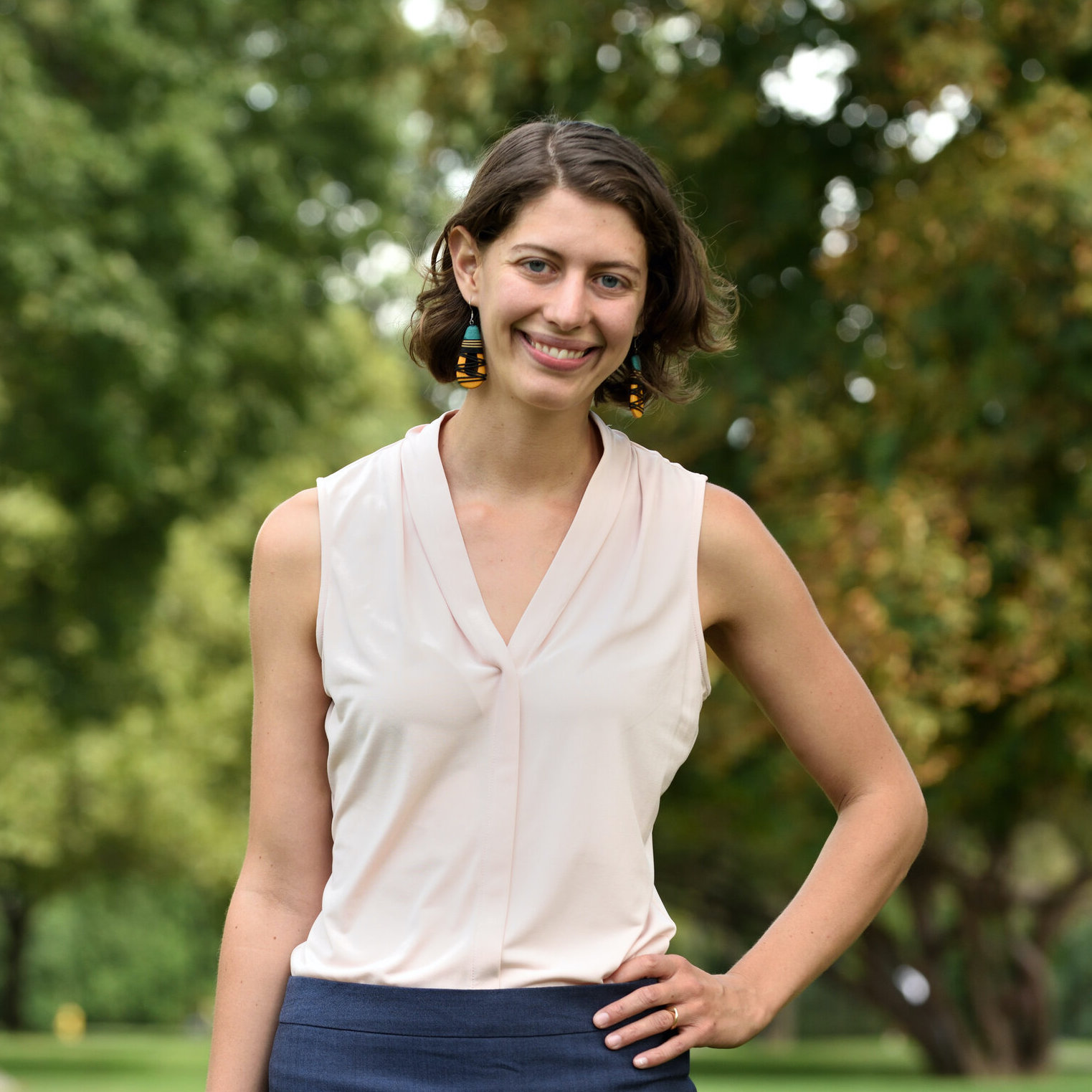 photo of a smiling white woman standing with her hand on her hip