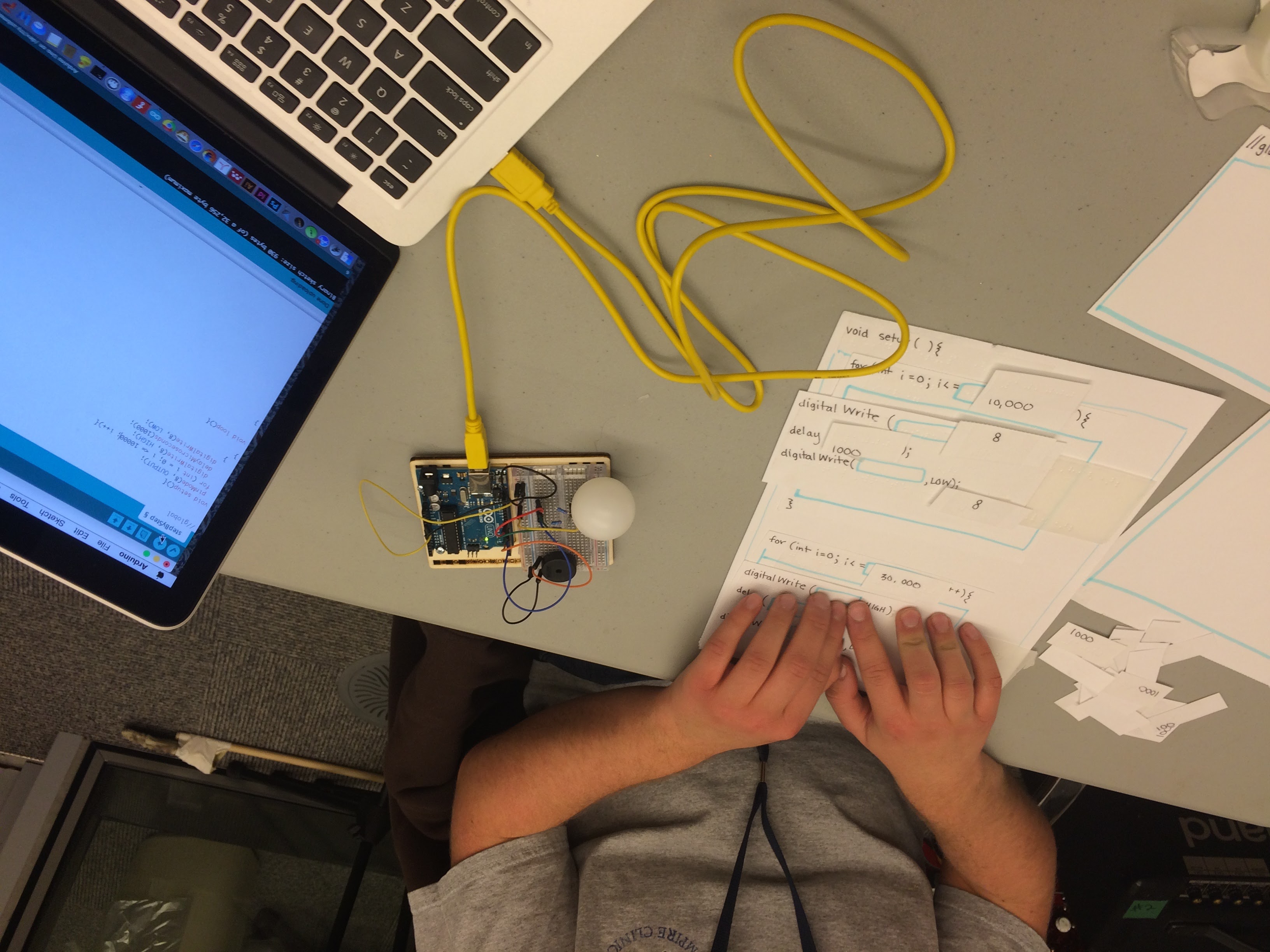 a laptop computer connected to an arduino microcontroller, hands reading braille next to the keyboard