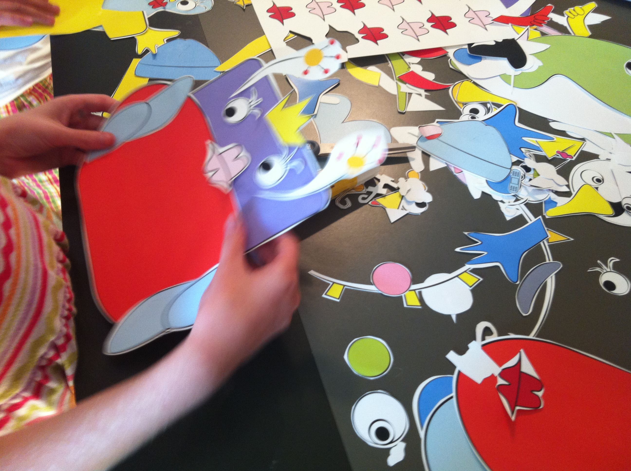 a child's hands making a collage with paper cutouts of faces