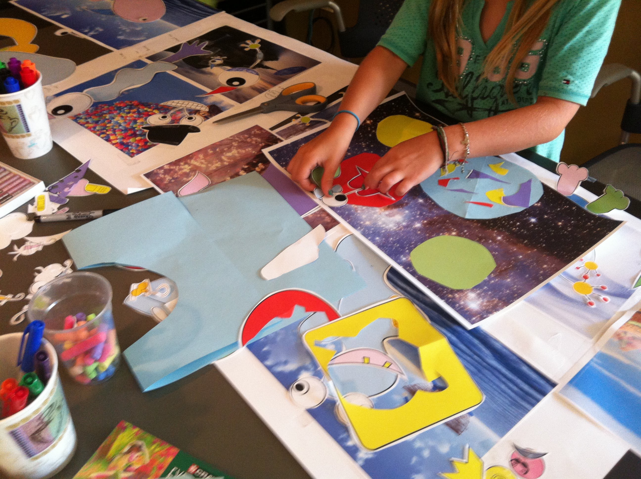 a child's hands making a collage with paper cutouts of faces